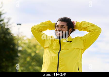 Afroamerikaner in leuchtend gelber Jacke lächelt beim Training an einem sonnigen Frühlingstag. Stockfoto