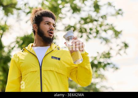 Ein Athlet genießt an einem hellen Frühlingstag ein erfrischendes Getränk im Freien und belebt sein Workout. Stockfoto