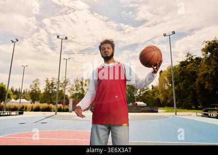 Ein junger Schwarzer spielt geschickt Basketball auf einem hellen Platz im Freien. Stockfoto