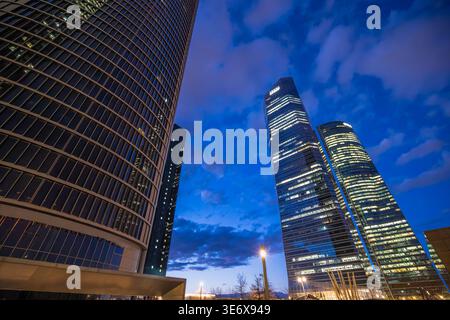 Madrid, Spanien - 14. März 2025 Ein flacher Blick auf moderne Wolkenkratzer im Geschäftsviertel Cuatro Torres in Madrid, beleuchtet vor dem Dämmerungshimmel. Stockfoto