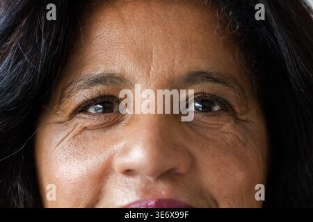 Afroamerikanerin mittleren Alters, die im Studio vor der Kamera steht, mit dunklem Lippenstift und Augen-Make-up Stockfoto