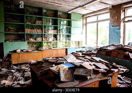 Ukraine, Pripyat, Tschernobyl-Ausschlusszone: Chaotische Anhäufungen von staubigen alten sowjetischen Lehrbüchern und Kinderbüchern auf Schreibtischen und auf dem Boden in heruntergekommenen elementaren en en Stockfoto
