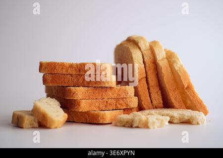 In Scheiben geschnittenes weißes Brot und Krümel auf weißem Hintergrund. Stockfoto