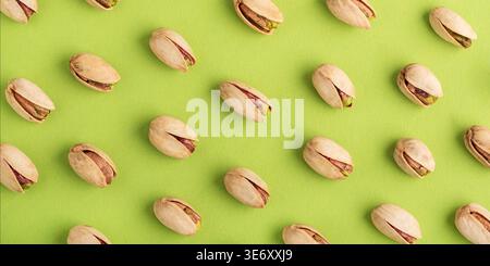 Minimalistisches Muster mit Pistazien in einem diagonalen Raster auf einem lebhaften grünen Hintergrund. Stockfoto