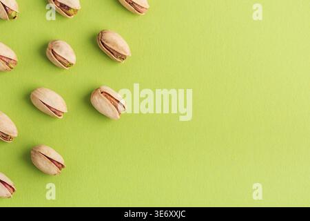 Minimalistisches Muster mit Pistazien in einem diagonalen Raster auf einem lebhaften grünen Hintergrund. Stockfoto