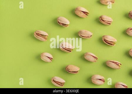 Minimalistisches Muster mit Pistazien in einem diagonalen Raster auf einem lebhaften grünen Hintergrund. Stockfoto