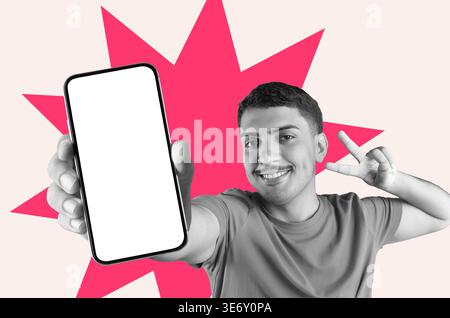 Der Mann zeigt Smartphone und Lächeln, während er das Friedenszeichen mit seinen Fingern in einem bunten Hintergrund gibt Stockfoto