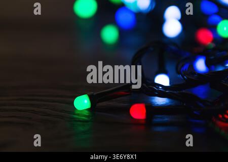 Weihnachtsbeleuchtung auf dunklem hölzernem Hintergrund mit Kopierraum Stockfoto