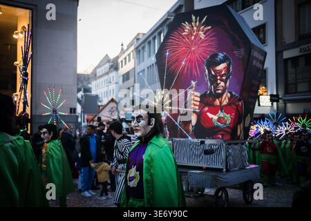 Basel, Schweiz - 10. März 2025: Blick auf kostümierte Figuren ziehen während der Fasnacht durch die Straßen der Stadt, deren leuchtende grüne Umhänge sich von ag abheben Stockfoto