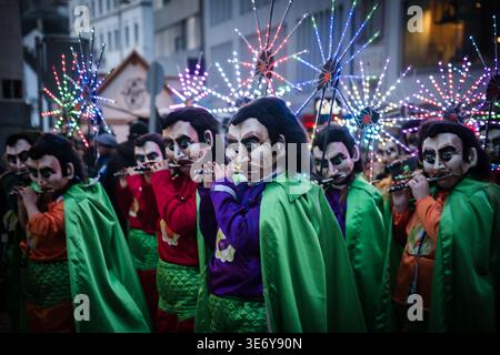 Basel, Schweiz - 10. März 2025: Der Blick auf maskierte Darsteller in lebhaften Kostümen zieht die Fasnacht hinunter, deren Flöten durch die historische Straße hallten Stockfoto