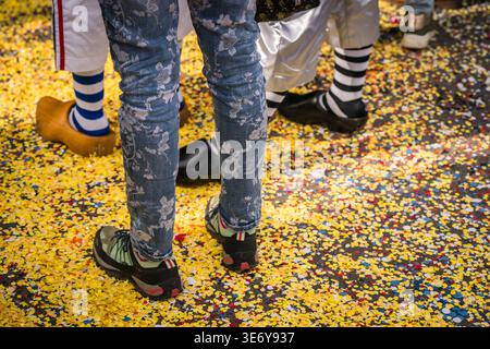 Basel, Schweiz - 10. März 2025: Blick auf Beine und Füße der kostümierten Teilnehmer inmitten eines Meeres aus leuchtend gelben Konfetti während der Fasnacht-Feier Stockfoto