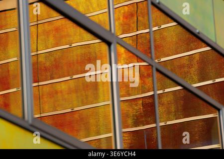Blick auf die Fassade des Gebäudes reflektiert ein warmes, goldenes Licht und schafft eine faszinierende Mischung aus Farben und Texturen in Almere, Flevoland, Niederlande. Stockfoto