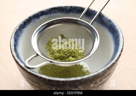 Matcha-Pulver in eine Schüssel am Holztisch, Nahaufnahme Stockfoto