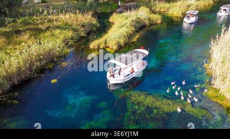 Von oben nach unten auf den kristallklaren Azmak River mit Tourbooten und Schilf in Akyaka Türkei Stockfoto
