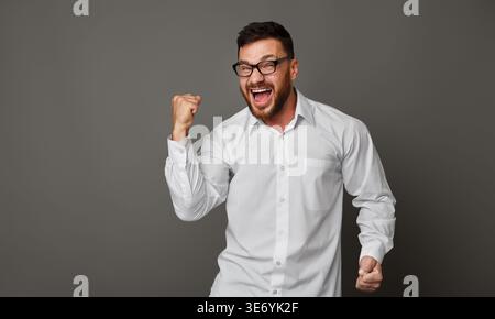 Junger aufgeregter Mann in Brille und fröhlichem Schreien Stockfoto