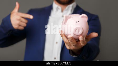 Geschäftsmann zeigt auf rosa Schweinebank aus nächster Nähe Stockfoto