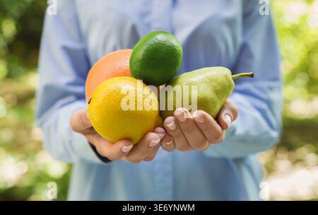 Frau, die verschiedene frische Früchte draußen in der Hand hält Stockfoto
