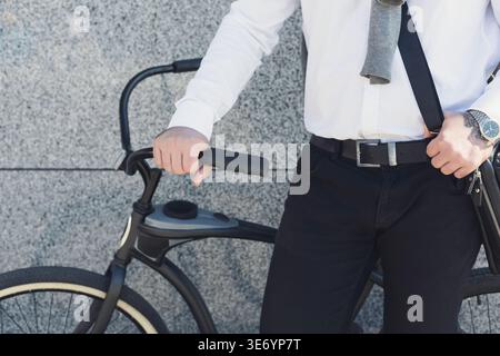 Geschäftsmann hält Hand an seinem Fahrrad, während er draußen steht Stockfoto
