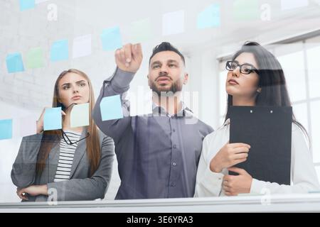Geschäftsmann, der seine Ideen auf Whiteboard setzt Stockfoto