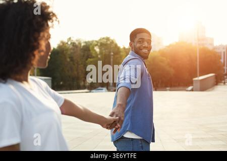 Ein Paar genießt einen sonnigen Tag zusammen, während er Hand in Hand in Hand in einem urbanen Ambiente geht Stockfoto
