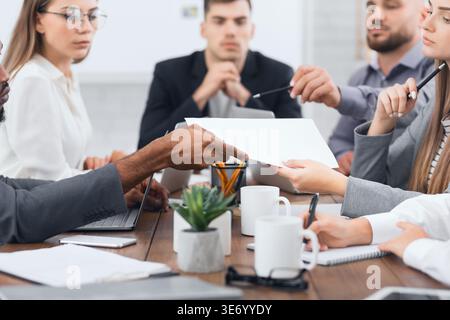 Der Manager übergibt Dokumente an seine Kollegen bei der Besprechung Stockfoto