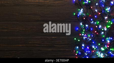 Bunte weihnachtslichter auf dunklem hölzernem Hintergrund Stockfoto