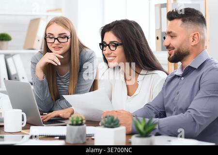 Drei Designer arbeiten im Büro gemeinsam an einem Notebook Stockfoto