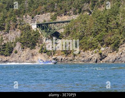 Whidbey Island, WA - 22. August 2025: Island Whaler Watching Boot im turbulenten Wasser der Deception Pass durch eine historische Brücke Stockfoto