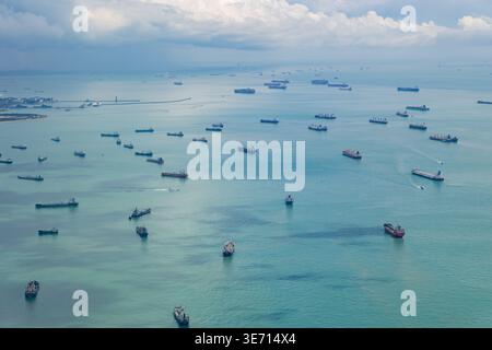 Zahlreiche Frachtschiffe und Öltanker ankerten im Meer nahe Singapur. Globale Seeverkehrslogistik und internationale Schifffahrtsindustrie unter einer Wolke Stockfoto