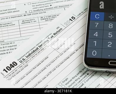 US-Steuerformular 1040 für das Jahr 2015 mit Taschenrechner-App auf Smartphone, die den Ausfüllen der Steuerformulare für das IRS veranschaulicht Stockfoto