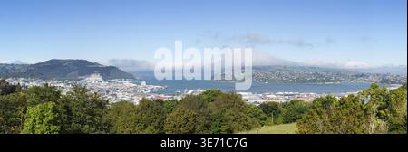 Weite Panoramalandschaft der Halbinsel Otago und der Bucht mit der Stadt Dunedin im Vordergrund und Wolken über den Bergen Stockfoto