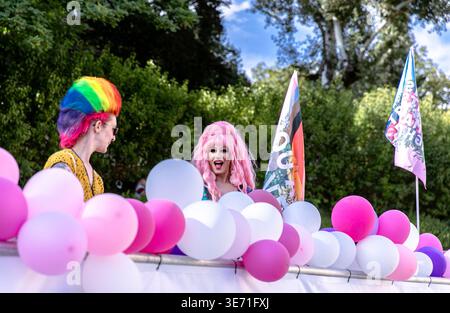 Klagenfurt, Österreich - 03. August 2024: Zwei Individuen mit einzigartigen Frisuren feiern die Pride Parade, umgeben von bunten Ballons A Stockfoto