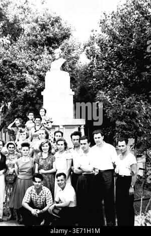 Slaviansk, 1959, Energy Technical College. Ein denkwürdiges Gruppenporträt der ersten Abschlussklasse vor einem Denkmal mit einer markanten Skulpturenbüste. Die jungen technischen Spezialisten, Männer und Frauen, posieren zusammen im Schatten üppiger grüner Bäume. Ihre ausgereifte Mid-Century-Mode, einschließlich Plisseedröcke und klassische Hemden, unterstreicht den Stil dieser Zeit, während sie stolz ihren bedeutenden Bildungsweg in der Stadt verewigen. Friedliches Leben im Donbass vor dem Konflikt. Stockfoto