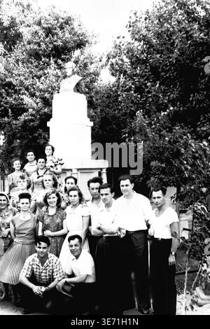 Slaviansk, 1959, Energy Technical College. Ein denkwürdiges Gruppenporträt der ersten Abschlussklasse vor einem Denkmal mit einer markanten Skulpturenbüste. Die jungen technischen Spezialisten, Männer und Frauen, posieren zusammen im Schatten üppiger grüner Bäume. Ihre ausgereifte Mid-Century-Mode, einschließlich Plisseedröcke und klassische Hemden, unterstreicht den Stil dieser Zeit, während sie stolz ihren bedeutenden Bildungsweg in der Stadt verewigen. Friedliches Leben im Donbass vor dem Konflikt. Stockfoto