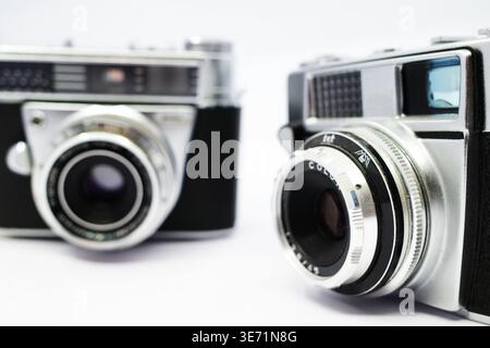 Nahaufnahme zweier analoger Vintage-Kameras. Beide haben silberne Gehäuse mit schwarzen Details. Die Objektive sind markant, mit Fokusringen und blendenmarkierung Stockfoto