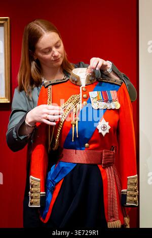 NUR Ein Mitglied der Royal Collection passt zeremonielle und militärische Kleidung an, die im Rahmen von „Queen Elizabeth II: Her Life in Style“ ausgestellt wird. Die größte Ausstellung der Mode der Königin, die jemals gezeigt wurde, zeigt etwa 300 Kleidungsstücke und Accessoires, etwa die Hälfte zum ersten Mal, und zeigt die Geschichte von Großbritanniens längster Herrscherin durch Kleidung, die in allen zehn Jahrzehnten ihres Lebens getragen wurde. Anlässlich des 100. Geburtstages der Königin wird die Ausstellung ab dem 10. April in der King's Gallery, Buckingham Palace in London, für die Öffentlichkeit geöffnet. Bilddatum: Donnerstag April Stockfoto