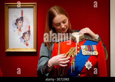 NUR Ein Mitglied der Royal Collection passt zeremonielle und militärische Kleidung an, die im Rahmen von „Queen Elizabeth II: Her Life in Style“ ausgestellt wird. Die größte Ausstellung der Mode der Königin, die jemals gezeigt wurde, zeigt etwa 300 Kleidungsstücke und Accessoires, etwa die Hälfte zum ersten Mal, und zeigt die Geschichte von Großbritanniens längster Herrscherin durch Kleidung, die in allen zehn Jahrzehnten ihres Lebens getragen wurde. Anlässlich des 100. Geburtstages der Königin wird die Ausstellung ab dem 10. April in der King's Gallery, Buckingham Palace in London, für die Öffentlichkeit geöffnet. Bilddatum: Donnerstag April Stockfoto