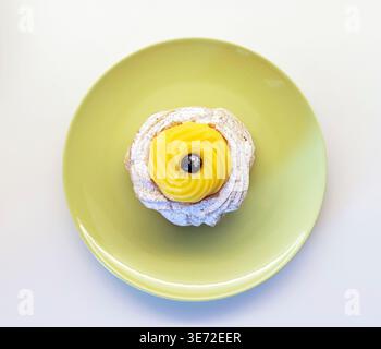Zeppole di San Giuseppe, traditionelles italienisches Choux-Gebäck mit weichem Ring, einem Schuss Vanillecreme und einer dunklen schwarzen Kirsche auf der Oberseite, die mit Puderzucker für die Feier des St. Josephs-Tages bestäubt ist Stockfoto
