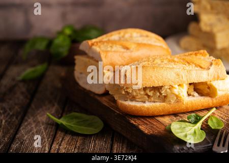 Spanisches Kartoffelomelette-Sandwich. Typisch spanisches Essen, Bocadillo de Tortilla espanola sehr beliebter Snack in Spanien auf weißem rustikalem Hintergrund Stockfoto