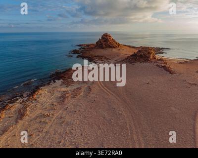 Aus der Vogelperspektive treffen Sie auf zerklüftete, sonnenverwöhnte Klippen auf das türkisfarbene Meer in einer Symphonie aus Erdtönen und Küstenschönheiten, Dhi Hamri, Socotra, Jemen. Stockfoto
