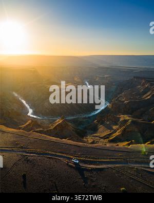 Aus der Vogelperspektive auf die zerklüftete Landschaft des Fish River Canyon, die vom gewundenen Fluss unter der goldenen Sonne geformt wurde, Fish River Canyon, Karas Region, Namibia. Stockfoto