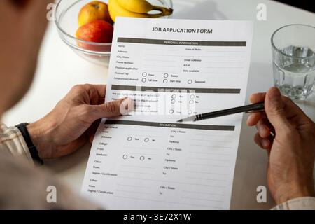 Ausfüllen des Bewerbungsformulars zu Hause mit Stift. Beschäftigungs-, Einstellungs- und Karrierekonzept Stockfoto
