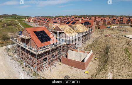Die Dächer einer Reihe neuer Häuser auf einer Baustelle mit integriertem Dach oder in-Dach-Solarpaneelen für billige und nachhaltige Energie in einer Öko-Umgebung Stockfoto