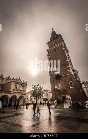 Der Rathausturm und die Tuchhalle auf dem Hauptmarkt in Krakau Polen an einem bewölkten Tag mit nassem Gehweg Stockfoto