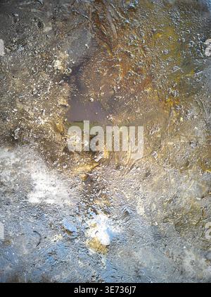 Nahaufnahme einer abstrakten Ölpest auf nasser Oberfläche. Satte Farben in Braun, Gold und Blau schaffen einen auffälligen, strukturierten Hintergrund. Stockfoto