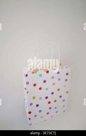 Bunte Geschenktüte aus Papier mit Punktmuster und Griffen, einfaches Verpackungskonzept für Shopping und Urlaub. Stockfoto