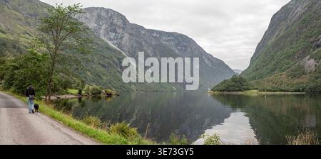 Eine Frau mit ihrem Hund wandert durch Naeroyfjord, Norwegen Stockfoto