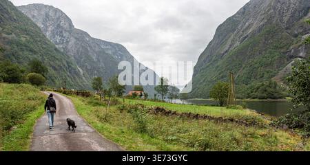 Eine Frau mit ihrem Hund wandert durch Naeroyfjord, Norwegen Stockfoto