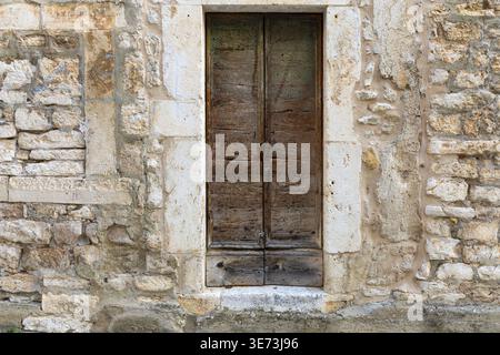Alte Holztür in verwitterter Steinmauer. Rustikale architektonische Details mit natürlichen Texturen und Vintage-Charakter. Stockfoto
