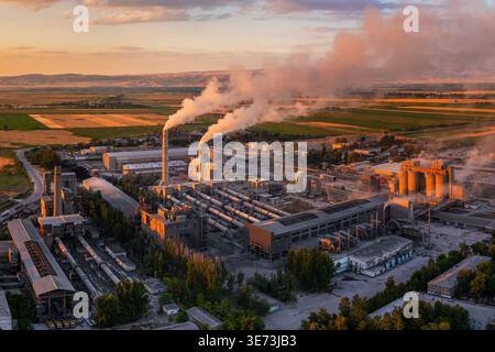 Drohnen-POV einer großen Zementfabrik mit berühmten langen horizontalen Drehrohröfen, hohen Schornsteinen und Industriebauten in Kirgisistan Stockfoto